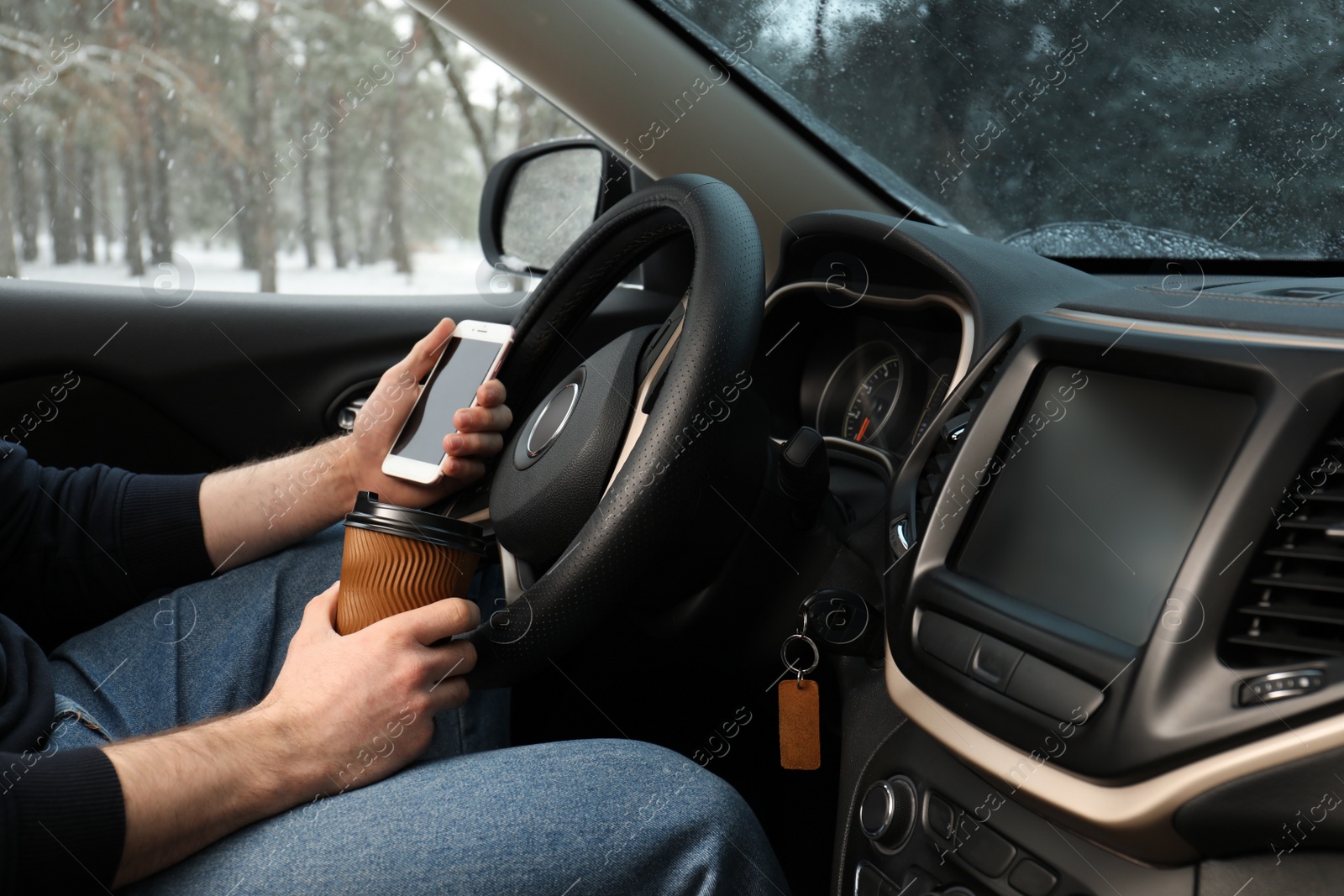 Photo of Young man with coffee and smartphone inside car, closeup