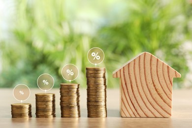 Image of Mortgage rate. Stacked coins, percent signs and wooden model of house