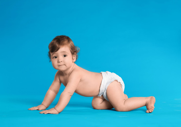 Photo of Cute little baby in diaper on light blue background