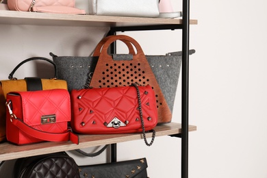 Photo of Shelving unit with stylish purses near white wall. Element of dressing room interior