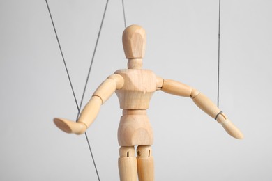 One wooden puppet with strings on light grey background