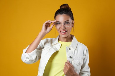Beautiful woman in eyeglasses on yellow background