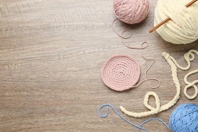 Photo of Flat lay composition with knitting threads and crochet hook on wooden table, space for text