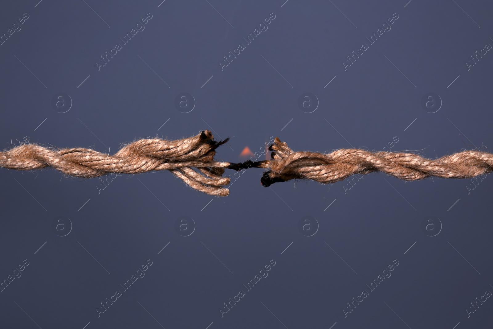 Photo of Burning rope at breaking point on dark background, closeup