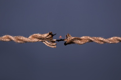 Burning rope at breaking point on dark background, closeup