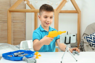 Cute little blogger with toy recording video at home