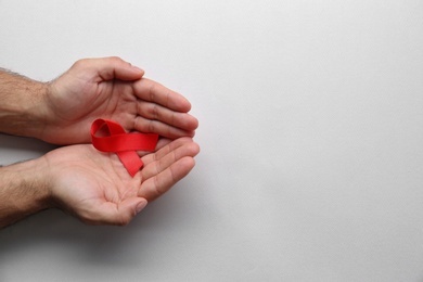 Photo of Man holding red awareness ribbon on white background, top view with space for text. World AIDS disease day