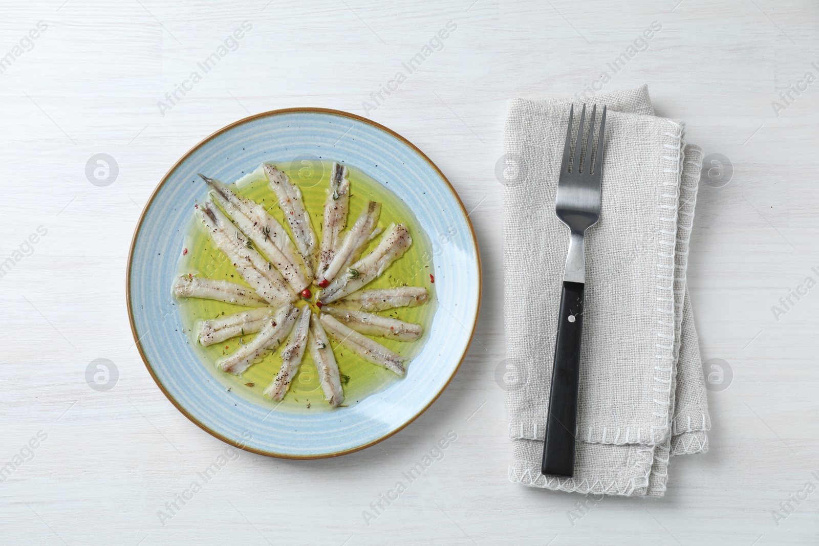 Photo of Tasty pickled anchovies with spices on white wooden table, top view