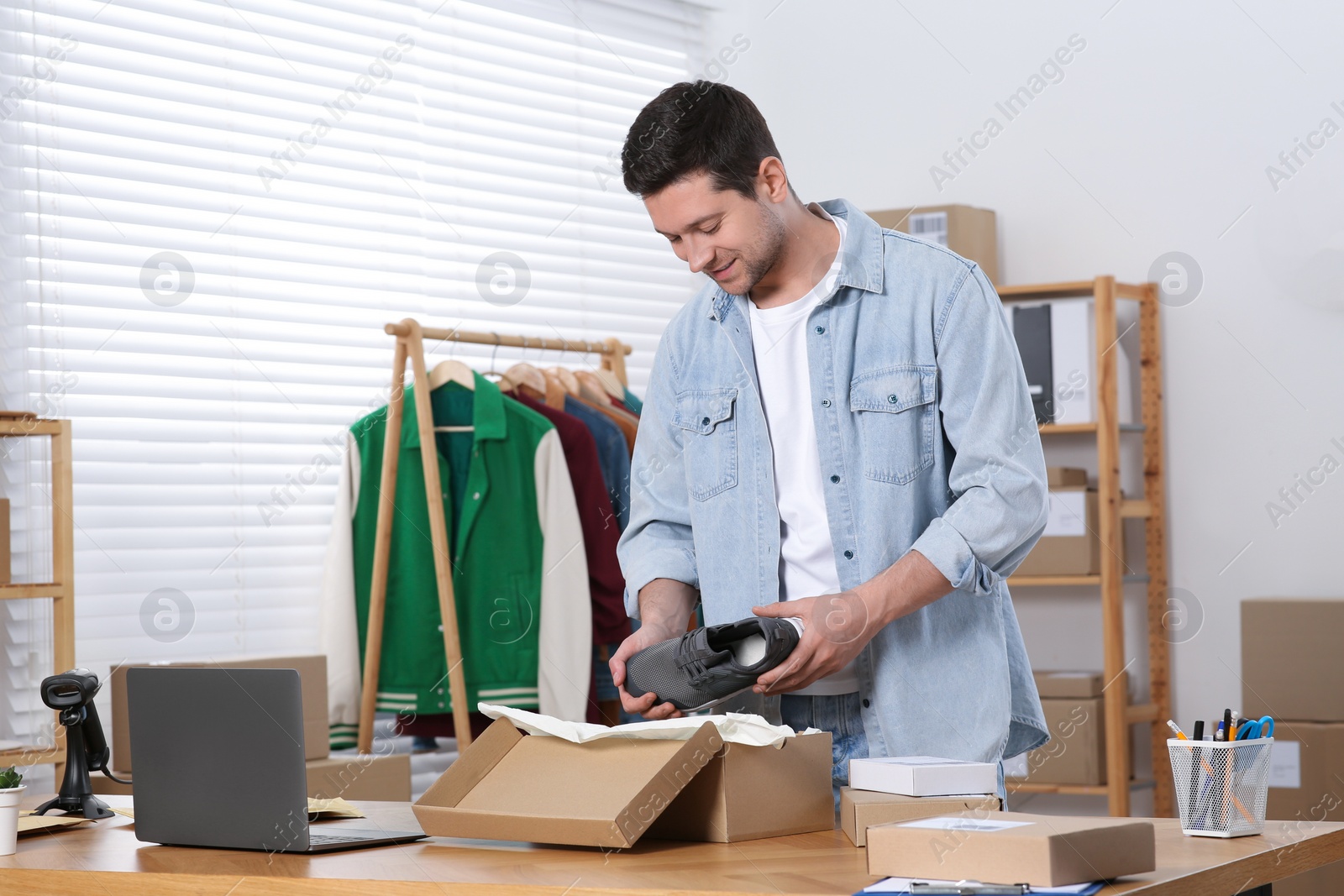 Photo of Seller packing shoes at workplace. Online store