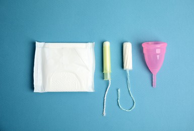 Photo of Tampon, pad and menstrual cup on blue background, flat lay