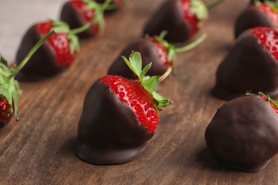 Photo of Chocolate covered strawberries on wooden board, closeup