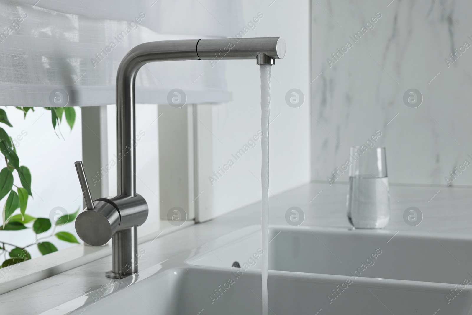 Photo of Stream of water flowing from tap in kitchen