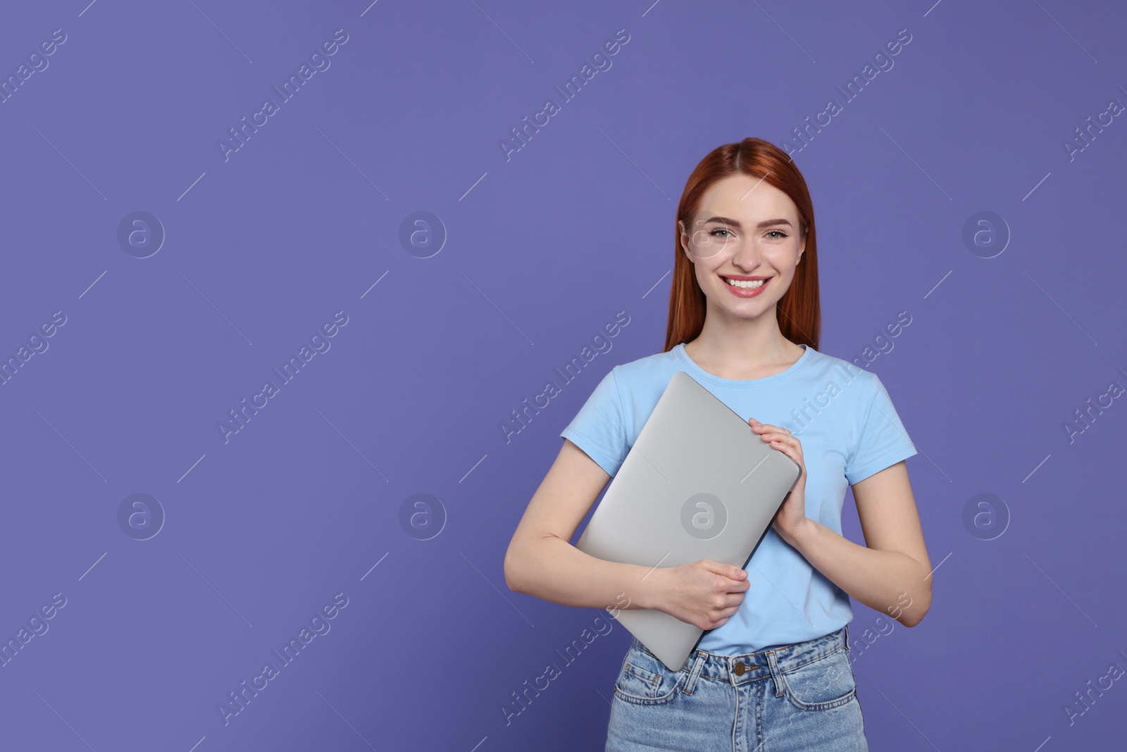 Photo of Smiling young woman with laptop on lilac background, space for text