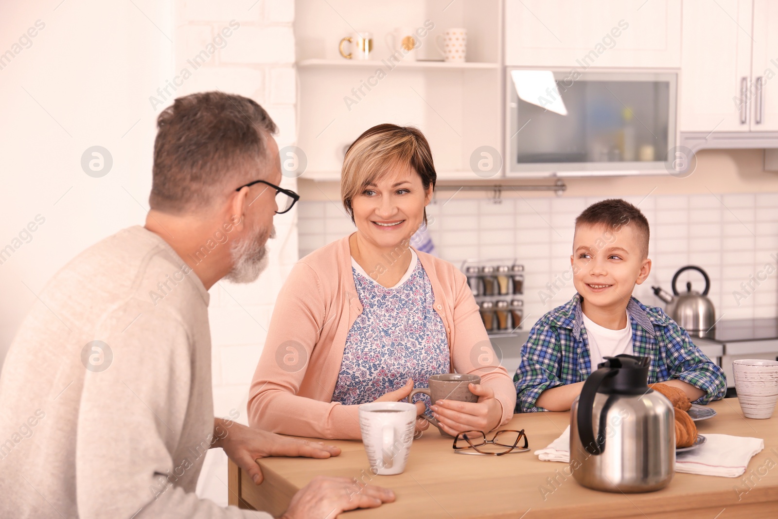 Photo of Happy senior couple having breakfast with little grandson at home