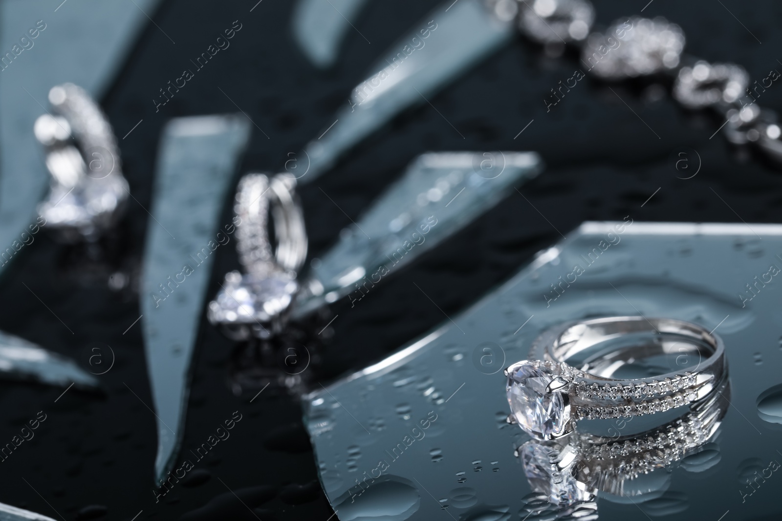 Photo of Luxury jewelry. Stylish presentation of elegant ring on black mirror surface with broken glass, space for text