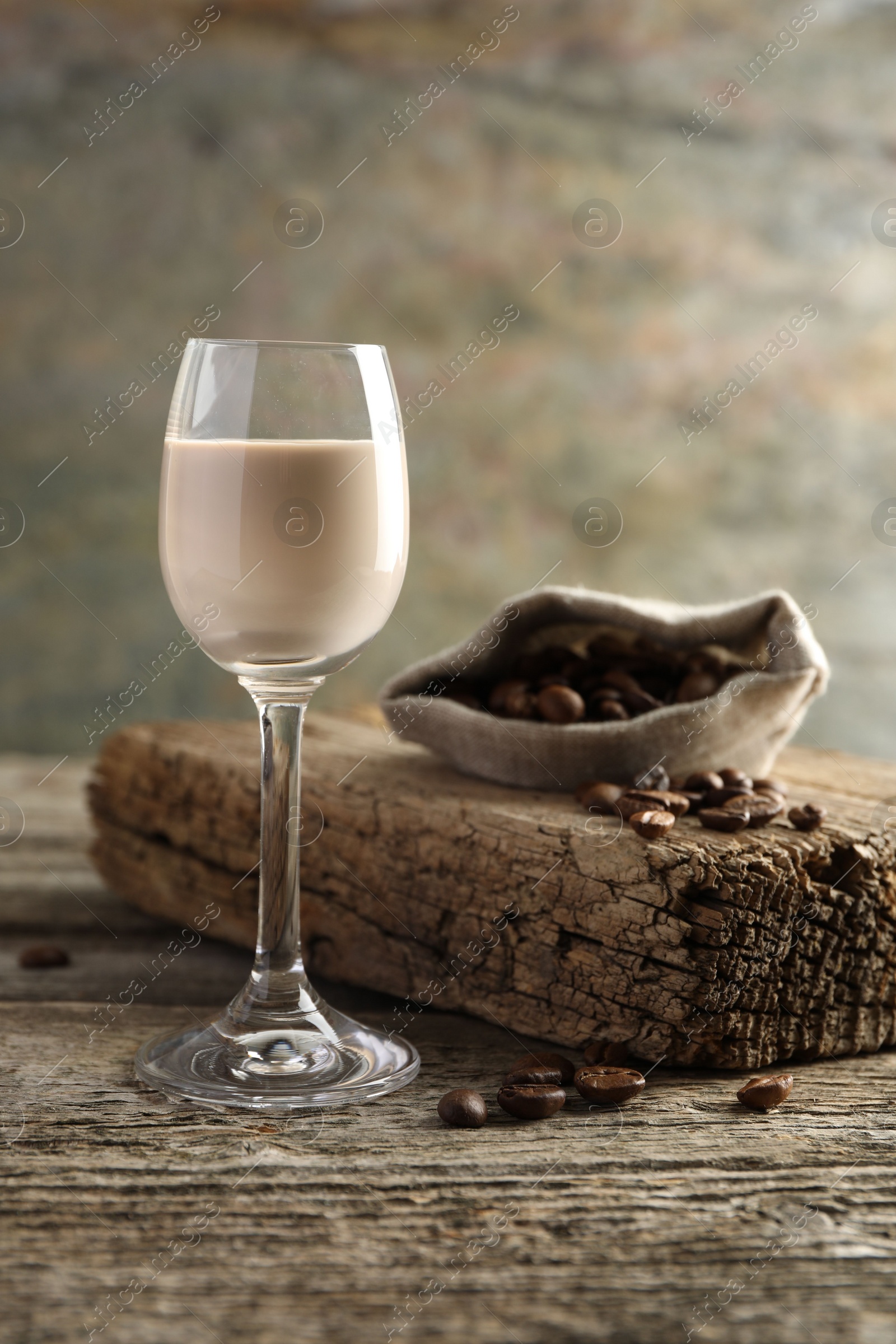 Photo of Coffee cream liqueur in glass and beans on wooden table