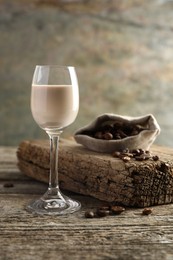 Coffee cream liqueur in glass and beans on wooden table
