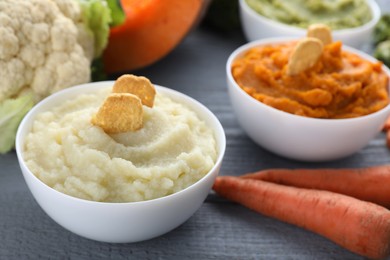 Photo of Bowls with different tasty puree and ingredients on light blue table, closeup