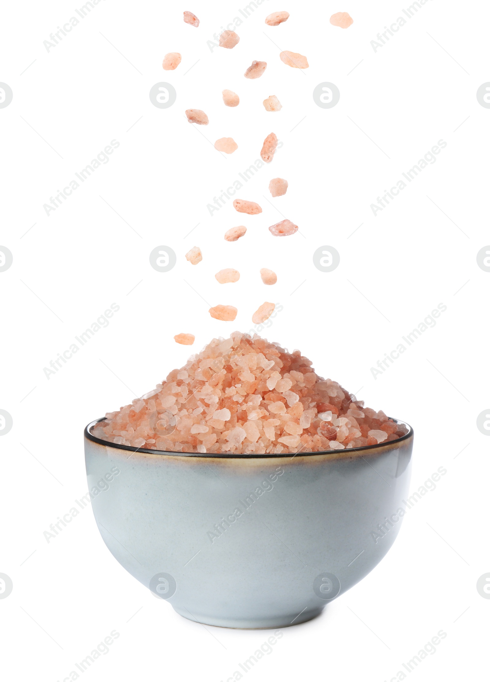 Image of Pink himalayan salt falling into bowl on white background