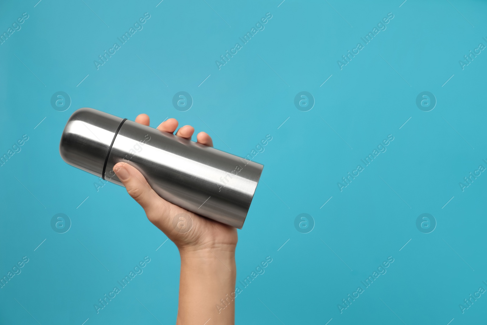 Photo of Woman holding modern thermos on light blue background, closeup. Space for text