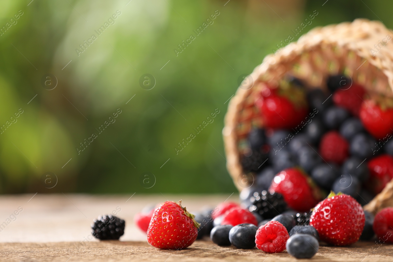 Photo of Different fresh ripe berries on wooden table outdoors. Space for text