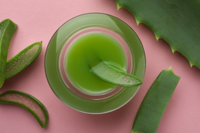 Photo of Jar with gel and cut aloe leaves on pink background, flat lay