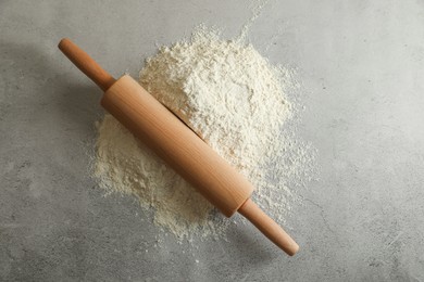 Flour and rolling pin on grey table, top view