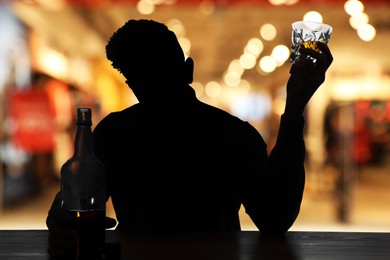 Image of Silhouette of addicted man with alcoholic drink in bar