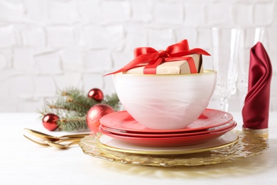 Festive dishware with gift and Christmas decorations on white table