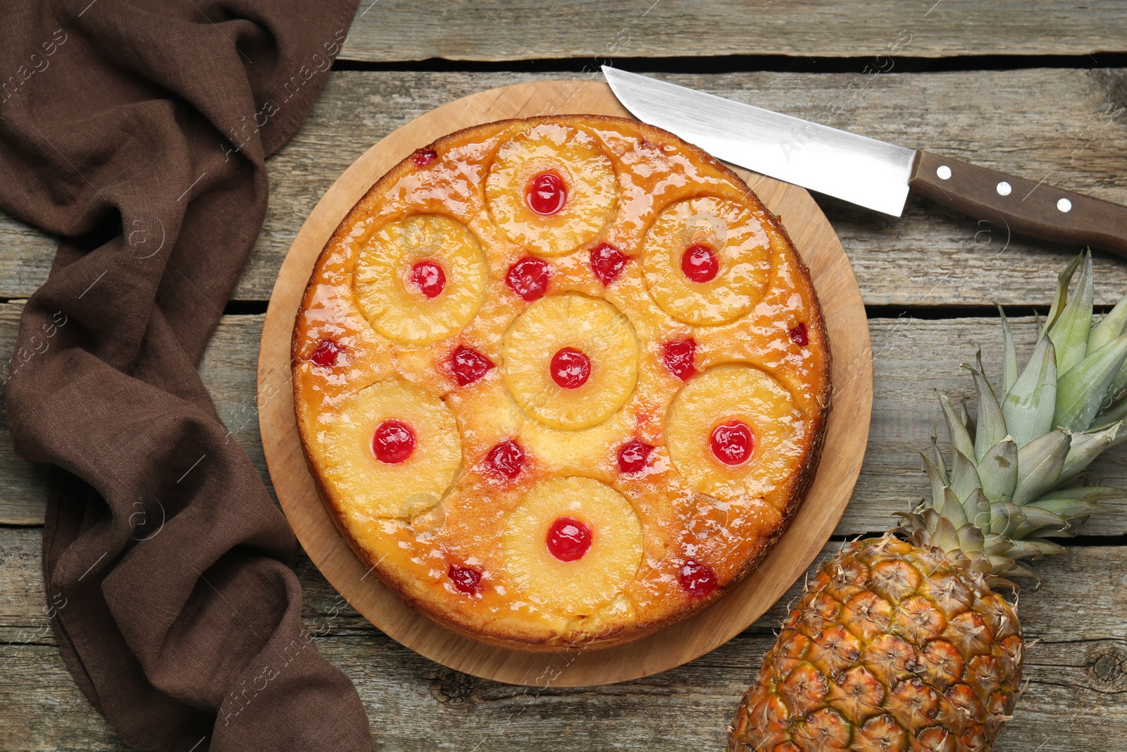 Photo of Tasty pineapple cake with cherries on wooden table, flat lay