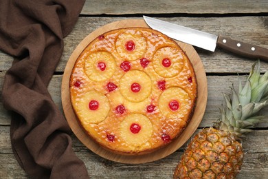 Tasty pineapple cake with cherries on wooden table, flat lay