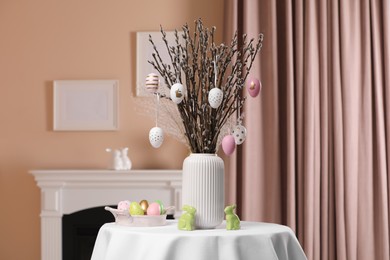 Pussy willow branches with festively decorated eggs and Easter bunnies on table at home
