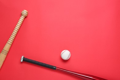 Photo of Baseball bats and ball on red background, flat lay. Space for text