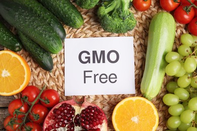 Photo of Tasty fresh GMO free products and paper card on wicker serving napkin, flat lay