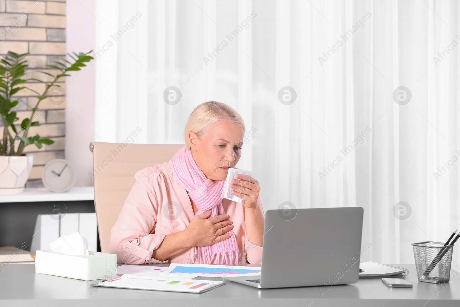 Photo of Ill mature woman suffering from cough at workplace