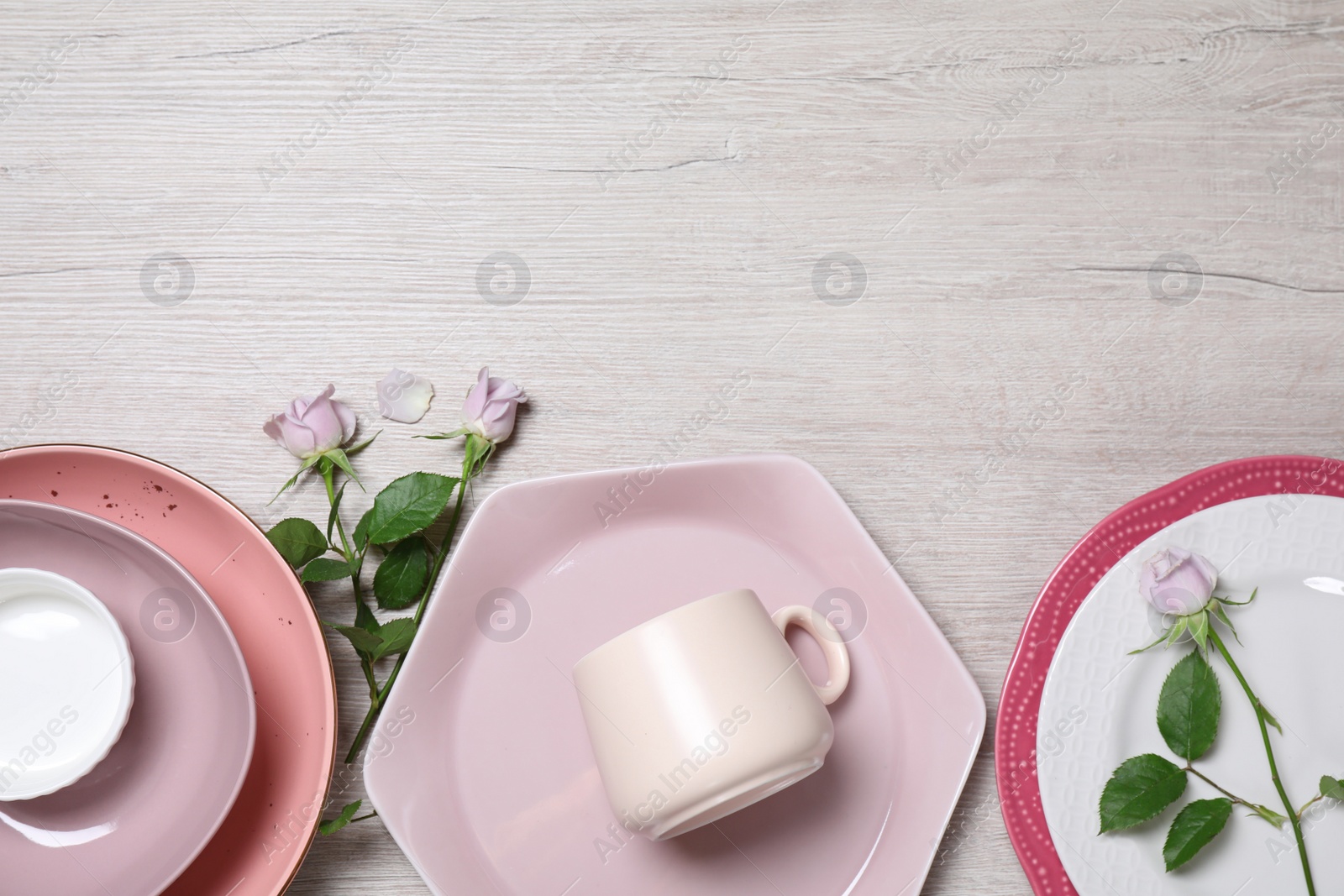 Photo of Flat lay composition with beautiful dishware and roses on white wooden table. Space for text