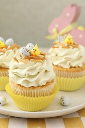 Photo of Tasty Easter cupcakes with vanilla cream on table, closeup