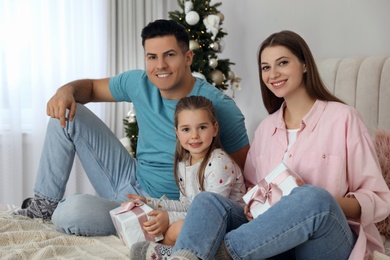 Portrait of happy family with Christmas gifts on bed at home