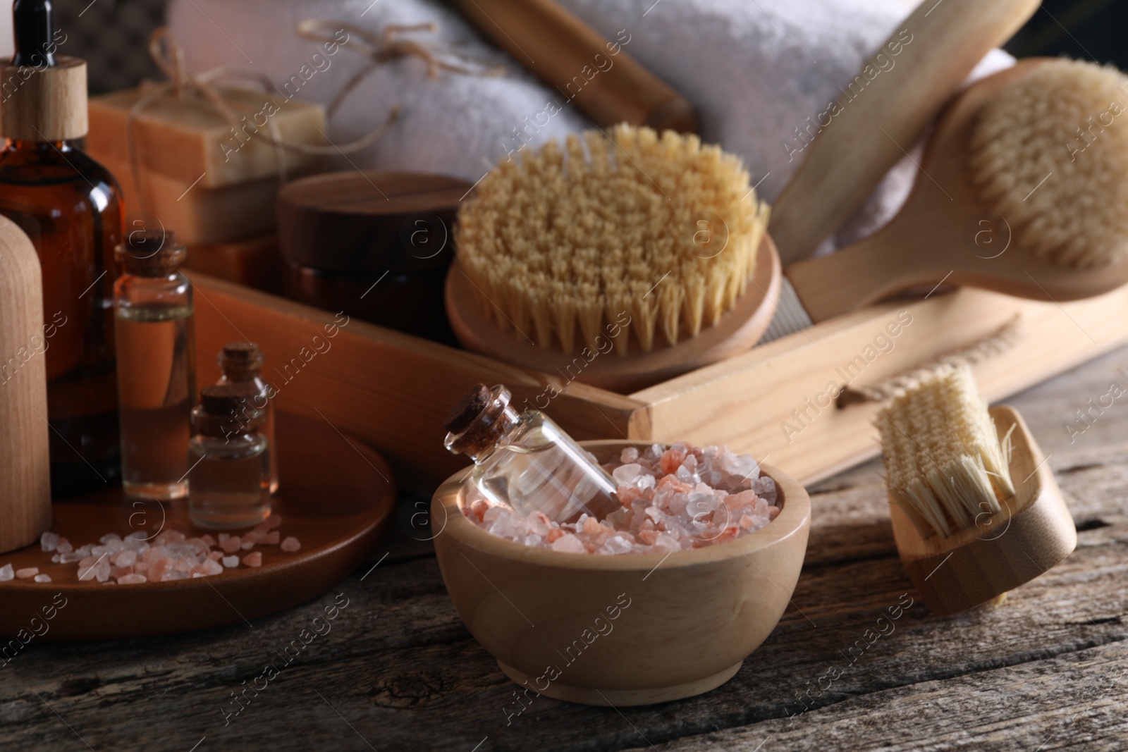 Photo of Spa composition. Bottles of cosmetic products, sea salt and brushes on wooden table