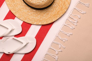 Photo of Beach towel, hat and flip flops on sand, flat lay