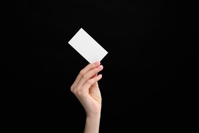 Woman holding blank business card on black background, closeup. Space for text