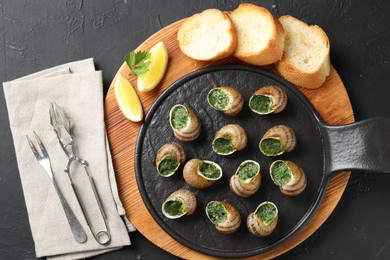 Photo of Delicious cooked snails served on grey textured table, flat lay