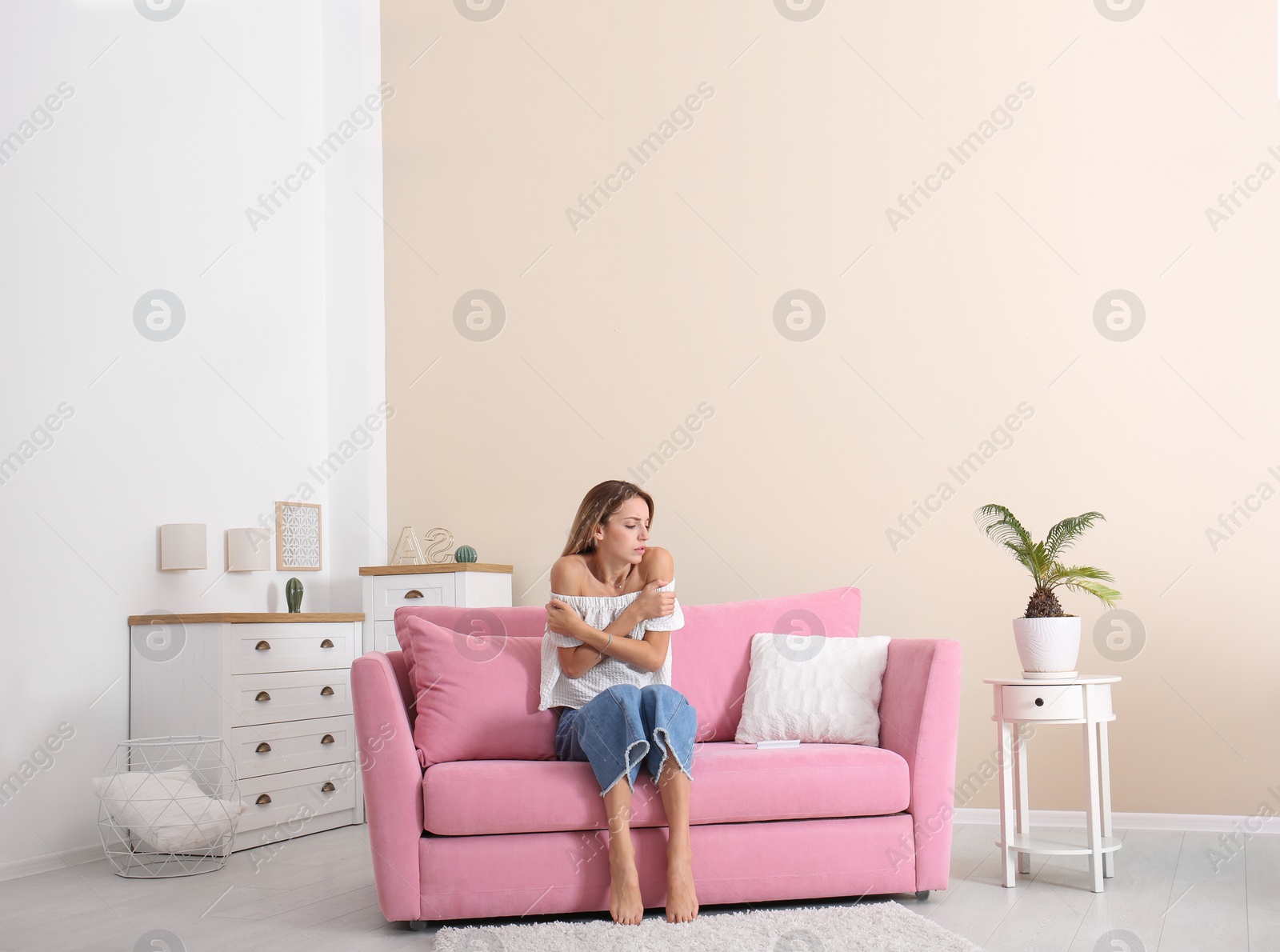 Photo of Young woman freezing under air conditioner at home