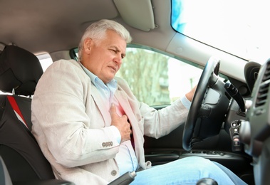 Senior man suffering from heart attack in car