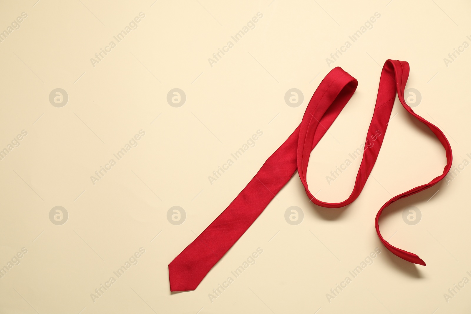 Photo of Red necktie on beige background, top view. Space for text