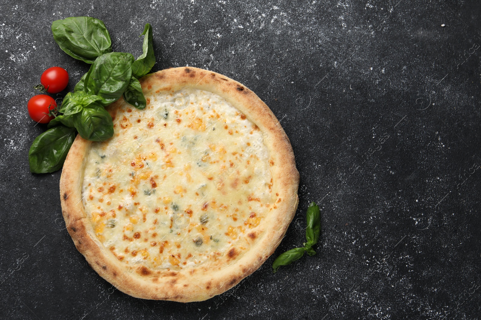 Photo of Delicious cheese pizza, basil and tomatoes on black textured table, flat lay. Space for text