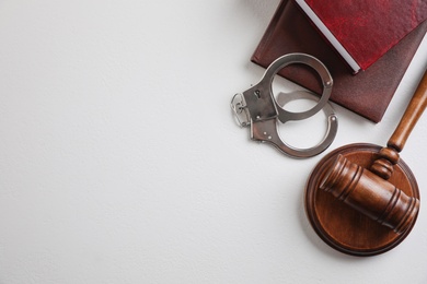 Flat lay composition with handcuffs and gavel on white background, space for text. Criminal law