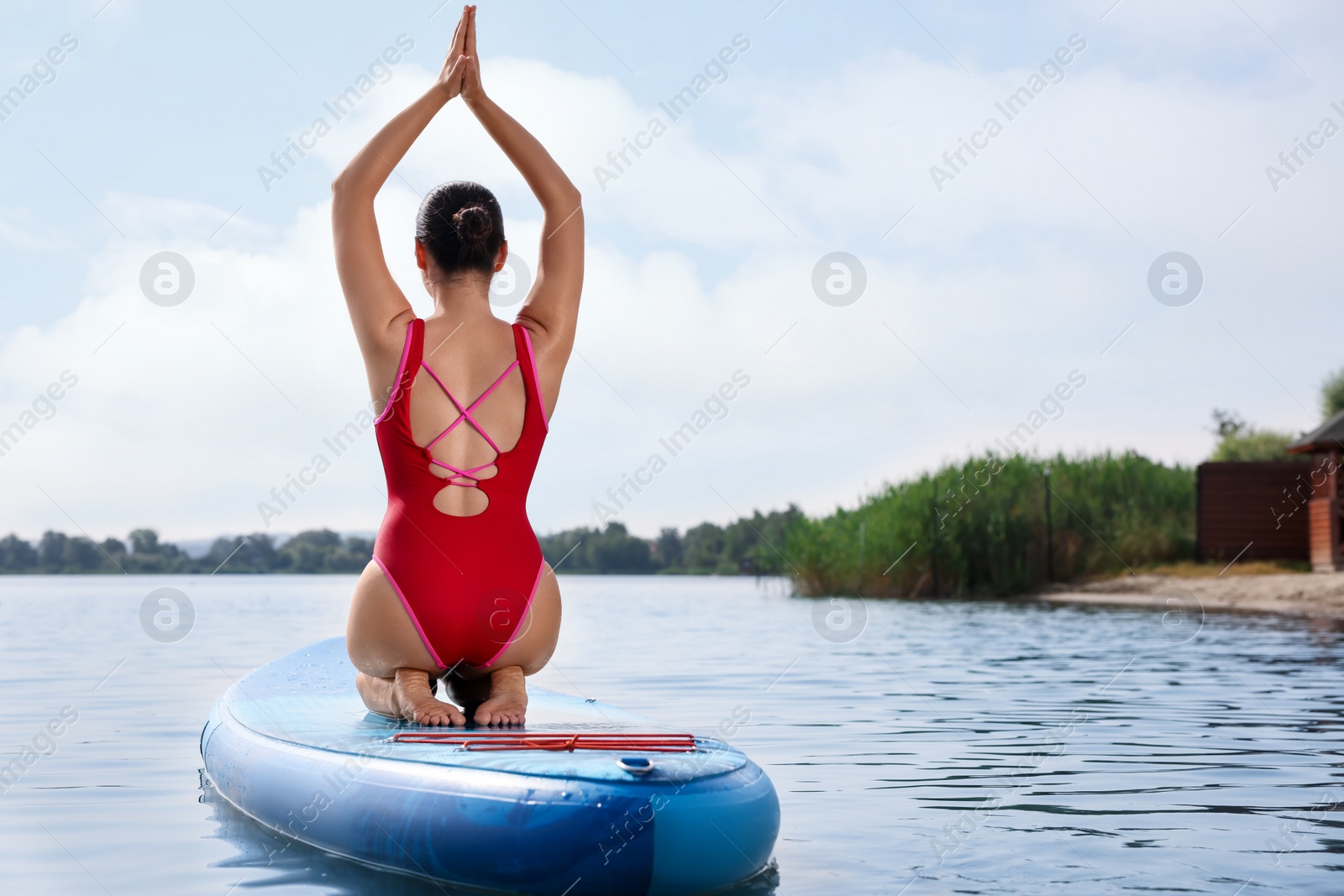 Photo of Woman practicing yoga on light blue SUP board on river, back view. Space for text