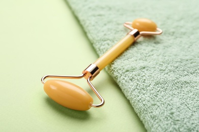 Natural face roller and towel on green background