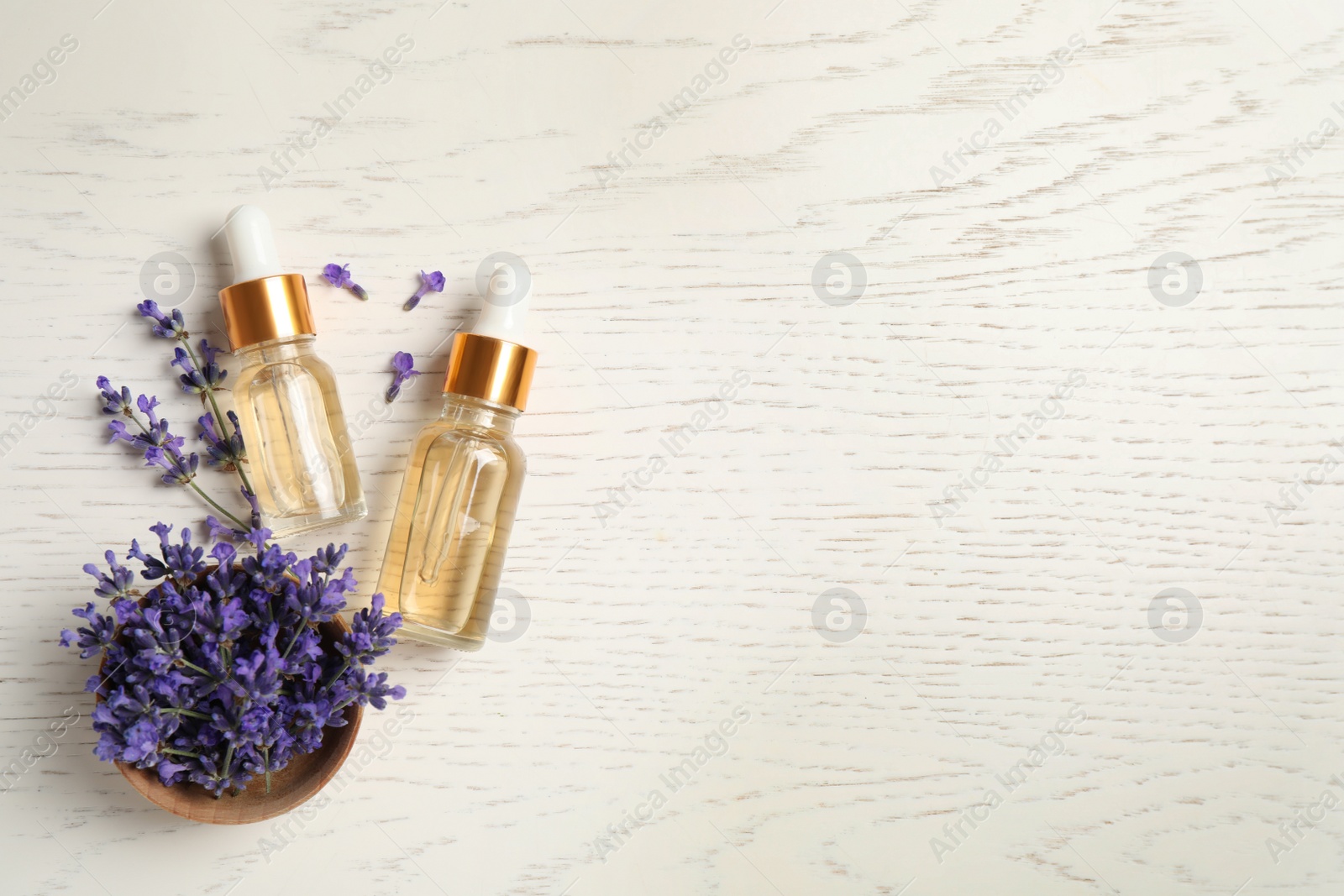 Photo of Flat lay composition with essential oil and lavender flowers on white wooden background. Space for text